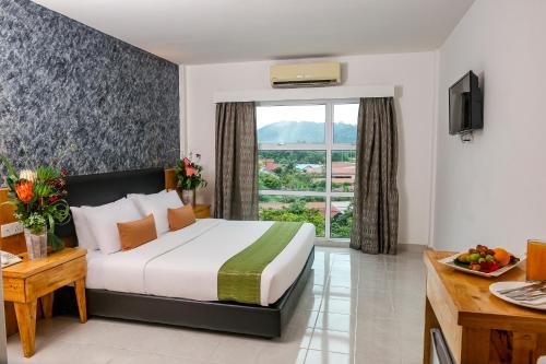 a hotel room with a bed and a window at Langkapuri Resort Langkawi in Pantai Cenang