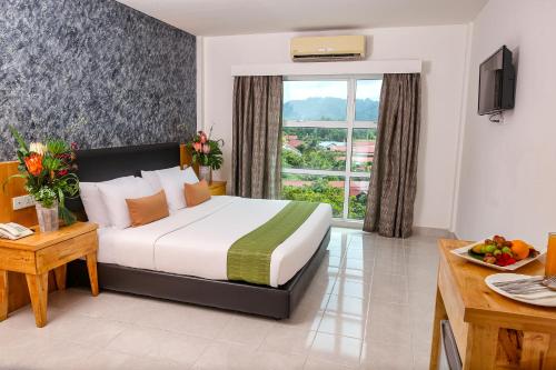 a hotel room with a bed and a window at Langkapuri Resort Langkawi in Pantai Cenang