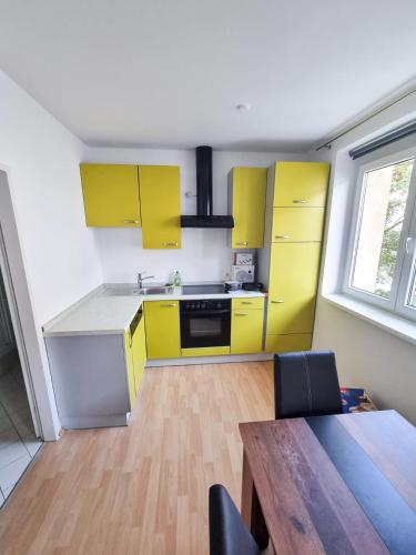 a kitchen with yellow cabinets and a wooden floor at ADSA Apartment Linz in Linz