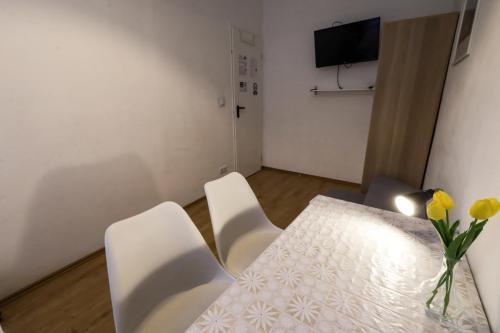 a table with white chairs and a vase of flowers on it at Budapest Pest-port apartment 4 rooms for 16 person in Budapest