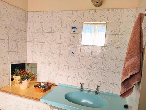 łazienka z niebieską umywalką i oknem w obiekcie Accommodation@42 Capital w mieście Pretoria