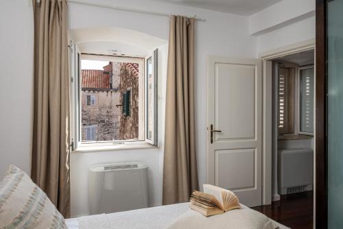 a bedroom with a window and a bed with a book at Villa Mirabilis, stunning superior villa, Dubrovnik Old Town in Dubrovnik