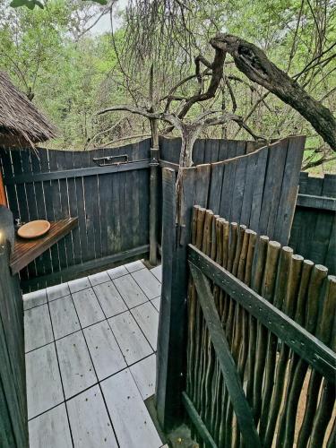 a wooden fence with a tree behind it at Off Beat Safaris Bush Lodge in Hoedspruit