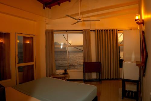 a bedroom with a bed and a window with the ocean at Peacock Beach Hotel Unawatuna in Unawatuna