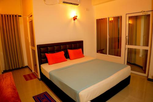 a bedroom with a bed with two red pillows at Peacock Beach Hotel Unawatuna in Unawatuna