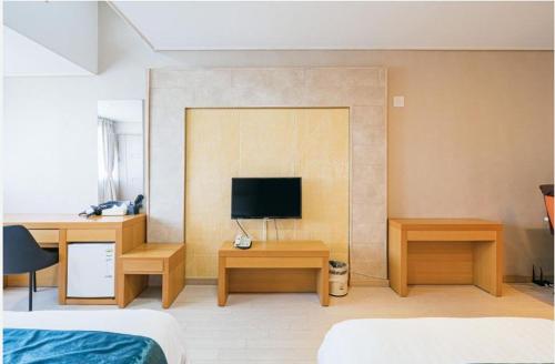 a bedroom with a bed and a television on a wall at R&T Hotel in Jeju