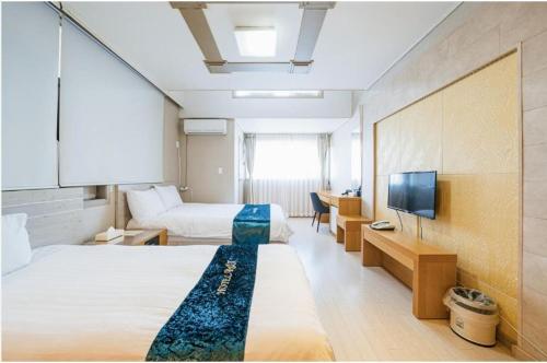 a hotel room with two beds and a flat screen tv at R&T Hotel in Jeju