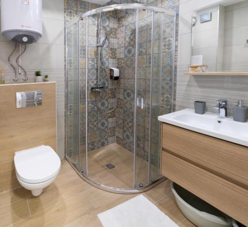 ein Bad mit einer Dusche, einem WC und einem Waschbecken in der Unterkunft New Modern & Cozy apartment with free parking in Warna