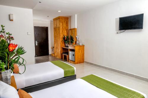 a hotel room with two beds and a flat screen tv at Langkapuri Resort Langkawi in Pantai Cenang