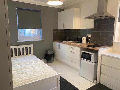 a small kitchen with white cabinets and a bed in it at Circle Guest House Bed Only in Southampton