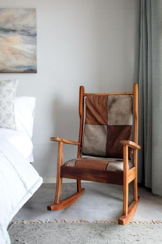a wooden chair sitting in a room next to a bed at Flamingo Beach in Swakopmund