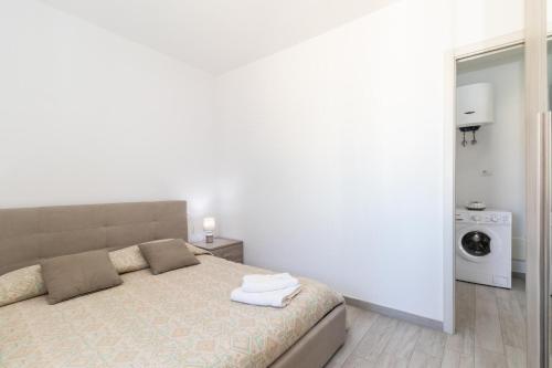 a white bedroom with a bed and a washing machine at Sardegna Isola Rossa Casa Mirta vista mare e wifi in Isola Rossa