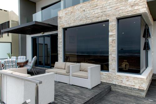 a patio with two white chairs and a large window at Flamingo Beach in Swakopmund