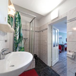 a bathroom with a white sink and a shower at Großer Gartenbungalow Nr 3 mit Terrasse - Strandvogtei Sellin in Ostseebad Sellin