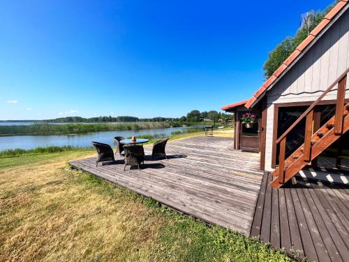 a wooden deck with a table and chairs next to a lake at Rõsna Puhkekeskus in Rõsna