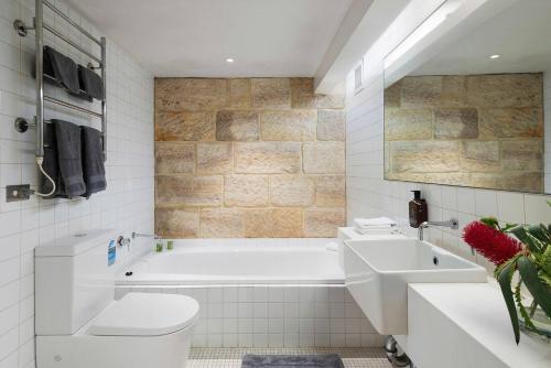 a bathroom with a tub and a toilet and a sink at Elegant Paddington Sandstone Cottage with Parking in Sydney