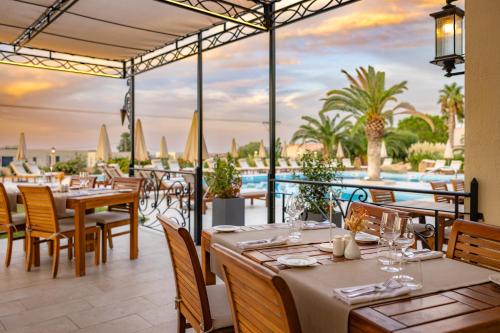 Hotel Corsica & Spa Serena في كالفي: مطعم به طاولات وكراسي ومطل على المحيط