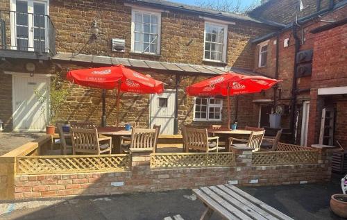 un patio con mesas, sillas y sombrillas en Bartholomew Arms, en Northampton