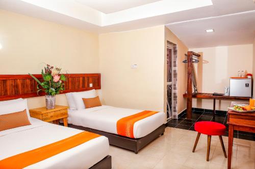a hotel room with two beds and a desk at Langkapuri Resort Langkawi in Pantai Cenang