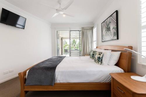 ein Schlafzimmer mit einem Bett und einem TV in der Unterkunft Rojo at Island Views—A Breezy Beachfront Retreat in Palm Cove