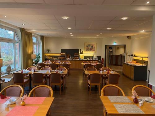 a restaurant with tables and chairs in a room at Andersen Hotel Birkenwerder in Birkenwerder