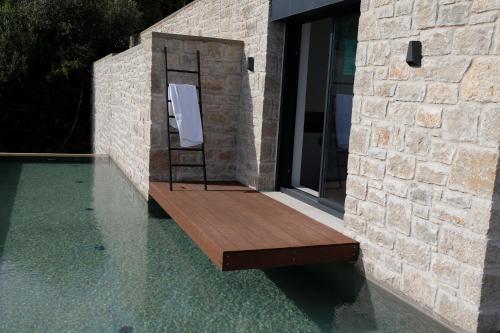 einem Pool mit einer Holzbank an der Seite eines Gebäudes in der Unterkunft Villa ODISSOS in Syvota
