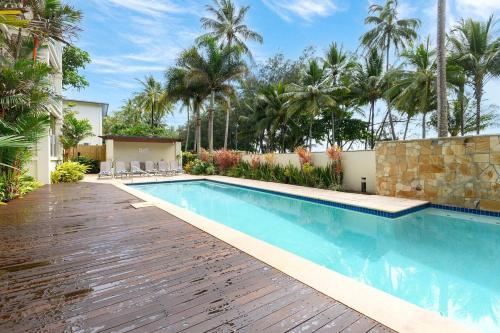 a swimming pool in a yard with palm trees at Azul at Island Views—Bask in Beachfront Living in Palm Cove