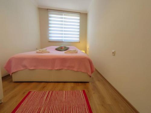 a bedroom with a bed with a pink blanket and a window at Lovely apartment in Küçükyalı in Istanbul