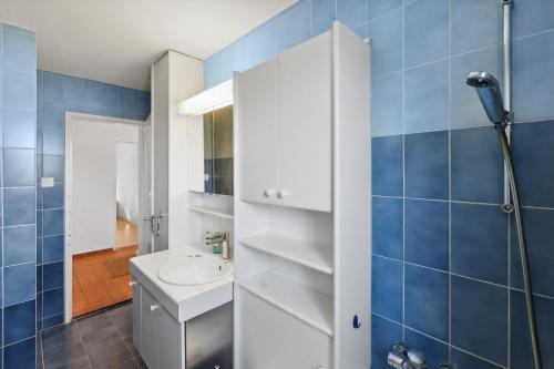 uma casa de banho com um lavatório branco e azulejos azuis em Charming and comfortable Apartment em Zürich
