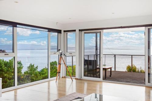 a room with large windows and a view of the ocean at 'Syrrah Serenity' Beachfront Bliss at Opossum Bay in South Arm