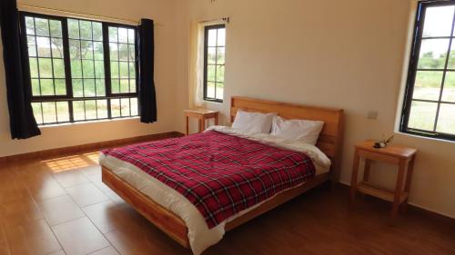 Samburu Dik-Dik House & Susuk Self-catering Cottage في Archers Post: غرفة نوم بسرير وبطانية حمراء ونوافذ