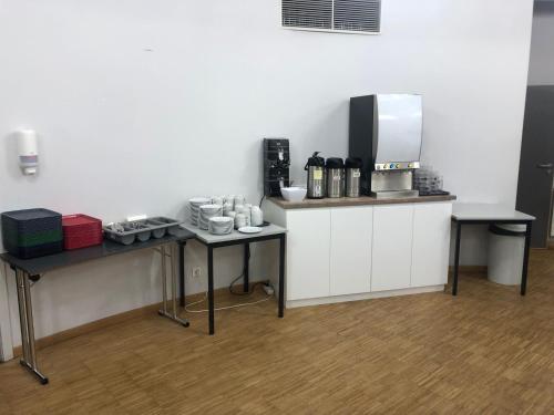 Hostel Van Gogh في بروكسل: مطبخ فيه طاولتين وصانع قهوة عليه