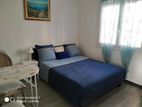 a bedroom with a bed and a table and window at CHAMBRES tout Confort,GARE TGV ,WIFI,Climatisation, parking,pt dejeuner inclus in Perpignan