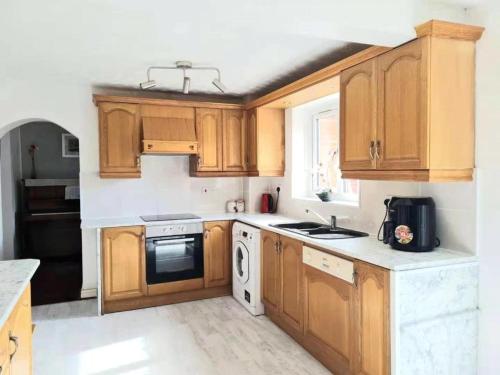 a kitchen with wooden cabinets and a stove top oven at Spacious family home in Malins Lee