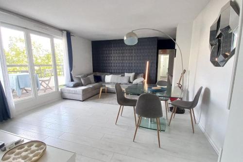 ein Wohnzimmer mit einem Tisch, Stühlen und einem Sofa in der Unterkunft Cosy home near Paris Olympics 2024, Rueil Malmaison in Rueil-Malmaison