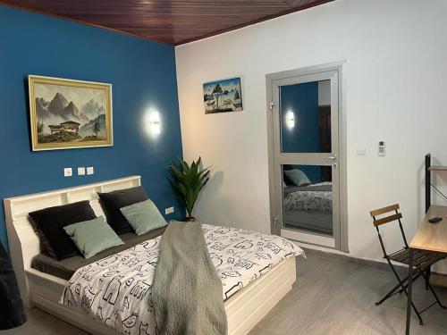 a bedroom with a bed with a blue wall at Mado Coliving - Studio Appart, Chambre coin cuisine, Chambre in Douala