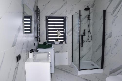 a white bathroom with a shower and a sink at Noclegi Beskidzkie Stodoły in Odrzechowa