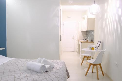 a white bedroom with a bed and a table at PARASIOU STUDIOS 102 διαμερίσματα στο κέντρο της πόλης in Komotini