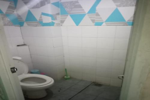 a bathroom with a toilet with blue and white tiles at OYO 93645 Akasia Budget in Bekasi