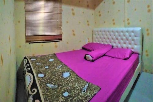 a bed with pink sheets and pillows in a room at OYO 93645 Akasia Budget in Bekasi