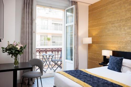 a hotel room with a bed and a desk and a balcony at Best Western Plus Hôtel Massena Nice in Nice