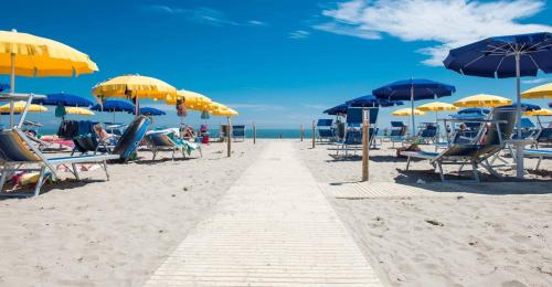 a sandy beach with chairs and umbrellas and the ocean at Spacious apartment with terrace - Beahost Rentals in Rosolina Mare