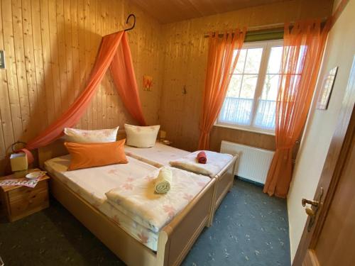 Schlafzimmer mit einem Bett mit orangefarbenen Vorhängen und einem Fenster in der Unterkunft Fewo Angermünde - Henriettenhof in Angermünde
