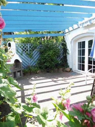 a patio with a blue building and flowers at Fewo Angermünde - Henriettenhof in Angermünde