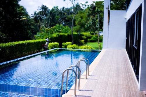 a swimming pool with two chairs next to a house at Townhome in Town in Ban Ba Ngan