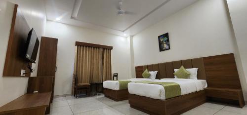 Habitación de hotel con 2 camas y TV en HOTEL GRAND EKTA, en Gorwa