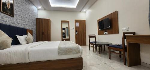 1 dormitorio con cama, mesa y TV en HOTEL GRAND EKTA, en Gorwa