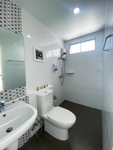 a white bathroom with a toilet and a sink at Townhome in Town in Ban Ba Ngan