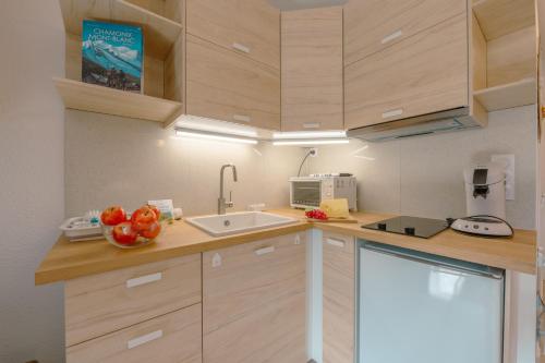 Elle comprend une petite cuisine avec des placards en bois et un évier. dans l'établissement Chamonix Sud - Genevrier 104 - Happy Rentals, à Chamonix-Mont-Blanc