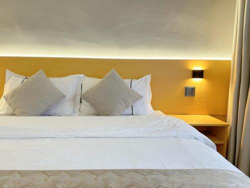 a bed with white pillows in a hotel room at Hemu House in Fenghuang